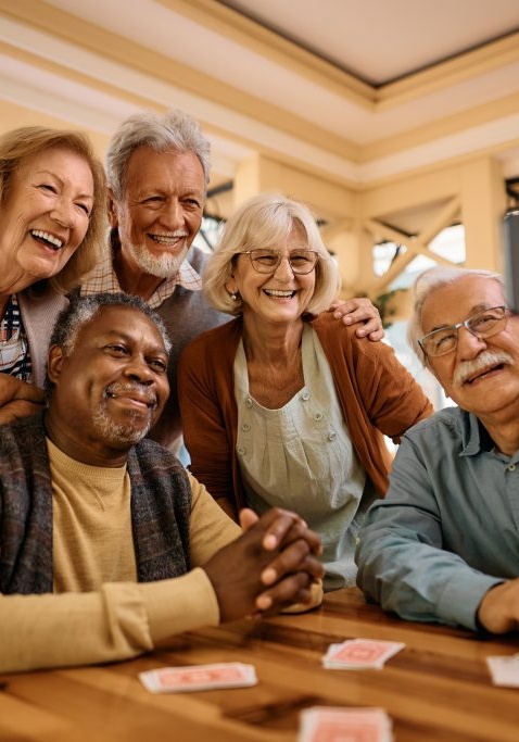 Cheerful senior having fun while taking selfie at retirement community. Multiracial group of happy senior people taking selfie with cell phone in nursing home.